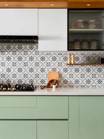 We call this kitchen the 'Garden of Eden' for its fresh green cabinets, floral patterned tiles, and warm veneer accents. The design includes a mix of solid and fluted glass shutters.