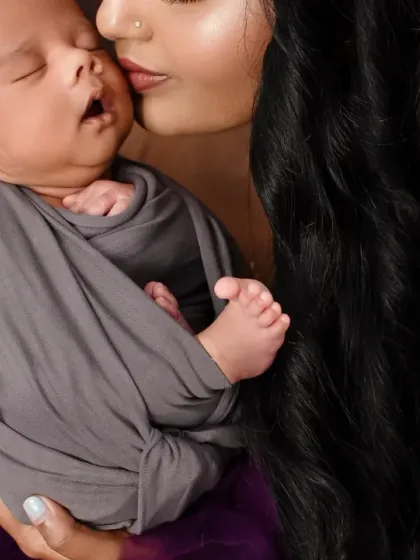 A close-up shot of a mother gently kissing her sleeping newborn's cheek. A simple, powerful expression of love.