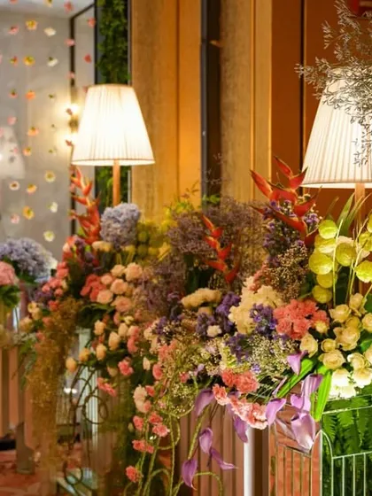 A close-up of the pastel floral arrangements, showing the beautiful mix of colors and textures. The soft lighting from the table lamps adds a touch of warmth to the daytime setup.
