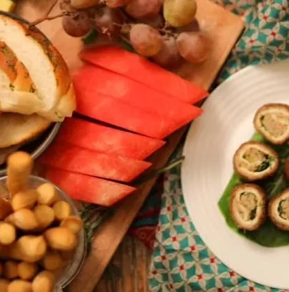 A glimpse of a catering spread in the making, with fresh watermelon, garlic bread, and savory rolls. It shows the variety of components I use to build a full menu.