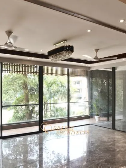 An empty, spacious living room with polished marble floors and large windows, showcasing the potential of the space before furnishing.