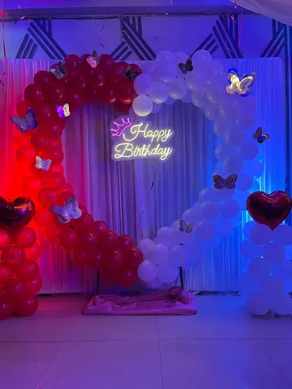 The red and blue lighting gives this birthday balloon setup a vibrant, party-ready look.