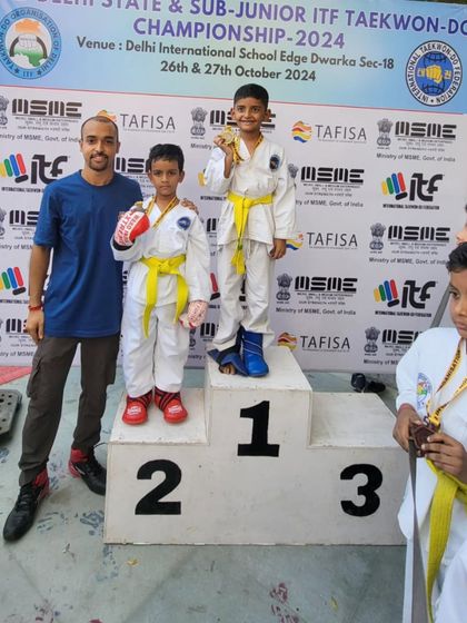 A coach stands with two of his youngest champions on the podium.