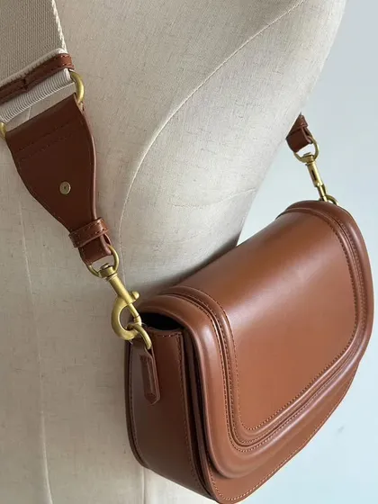 A mannequin showing the Noble bag worn with the wide fabric strap as a shoulder bag. This angle shows how comfortably it sits against the body.
