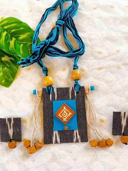 This image provides a clear, straight-on view of the grey Ikat and turquoise necklace set, highlighting its symmetrical design and rustic tassels.