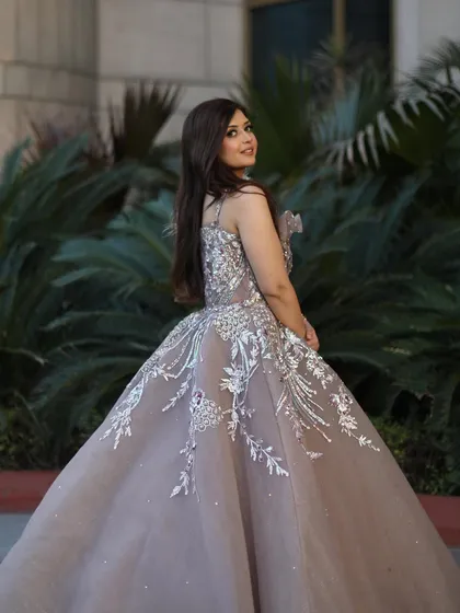 Our model looking radiant in the rose gold organza gown. The soft, warm tones of the dress are perfect for a romantic evening event, and the feather details add a modern, fashionable touch.