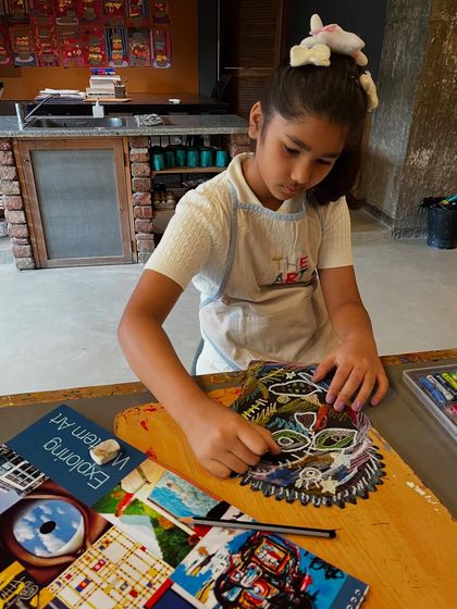A young artist is deeply focused on adding details to her Basquiat-style artwork, learning about layering colors and textures.