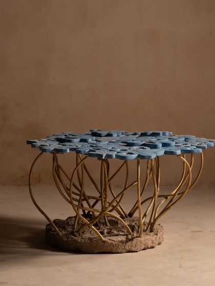 The full Gul Table, a stunning centerpiece for any living area. This piece unfolds like a botanical tapestry, inviting you to appreciate the blend of raw concrete, elegant brass, and delicate floral forms.