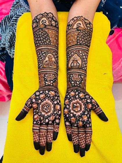 This engagement mehndi features beautiful peacock motifs and the couple's initials, 'S' and 'B', inside floral mandalas. The fingertips are kept dark for a striking contrast.