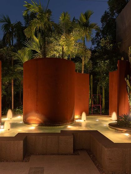 The Corten steel water feature at KEUS, illuminated at night. The warm lighting on the rusted steel and bubbling water creates a dramatic and sophisticated focal point in the commercial landscape.