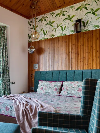 A detail of the master bedroom at Valley of Dreams, showing the layering of textures. The warm fluted pine paneling, foliage-print wallpaper, and soft floral fabrics come together to create a space that feels both grounded and dreamlike.