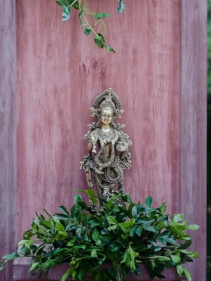 A brass deity placed against a wooden backdrop by the pond, integrating spiritual elements into the decor.