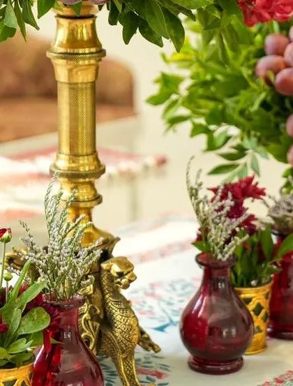 This shot shows the layering of elements on the table. Notice the tall brass candle stand, the smaller red vases, and the bunch of grapes, all creating a sense of depth.