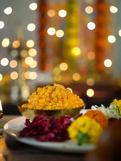 A bowl of sweet boondi against a backdrop of Diwali lights. The shallow depth of field creates a beautiful, dreamy effect, making the festive scene feel warm and inviting.