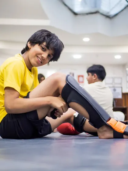 A moment of rest and a confident smile between rounds. Training is tough, but our program ensures kids feel accomplished and positive about the hard work they put in.