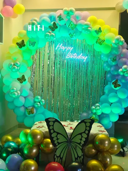 A beautiful rainbow balloon circle with a shimmer backdrop and butterfly accents, perfect for a vibrant birthday party.