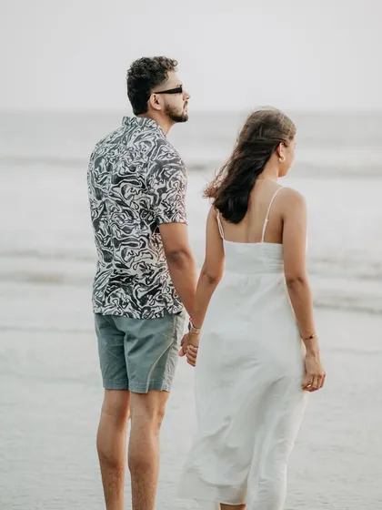 Looking towards the future together. A classic pre-wedding pose on the beach, holding hands and gazing at the sea.