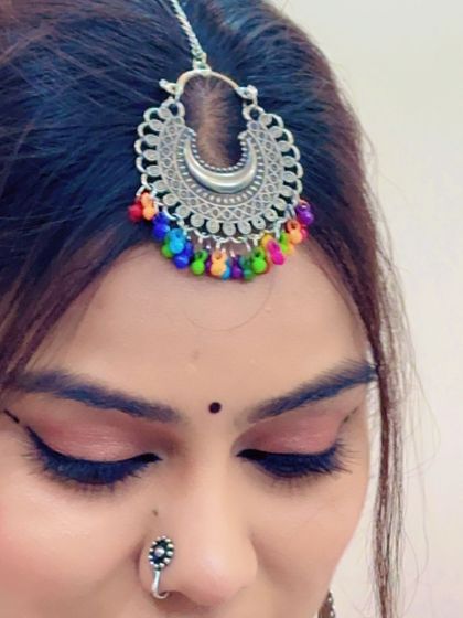 A close-up of a silver maang tikka with colorful beads, a perfect accessory to add a pop of color to your Garba outfit.