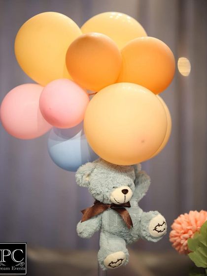 A close-up of a floating teddy bear centerpiece. This simple yet creative detail adds height and fun to the table decor for a "We Can Bearly Wait" themed baby shower.