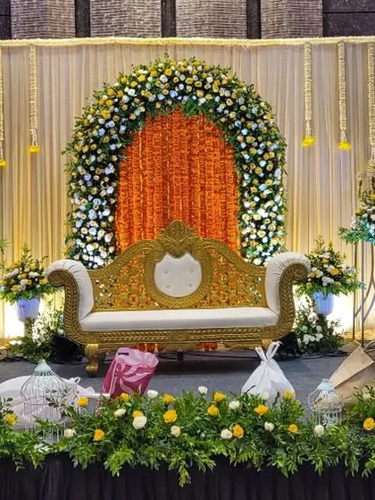 For this ring ceremony, we designed a vibrant stage with a central arch of fresh yellow and white flowers against a rich orange backdrop. The hanging floral strings and elegant couple seating complete this traditional yet modern look.