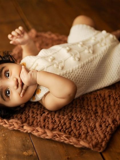 So many expressions in one little face. This baby is lying on a rustic mat, looking up with curiosity.