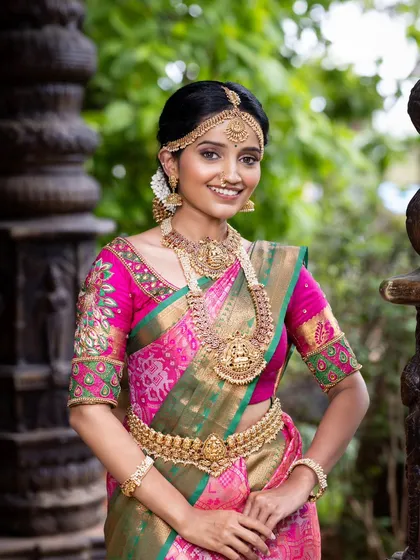 A classic South Indian bride in a stunning pink and green Kanjivaram silk saree. This timeless combination is perfect for Muhurtham ceremonies, offering traditional elegance and grace. The pure silk drapes beautifully for photos and makes you feel rooted in tradition.