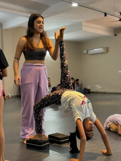 We celebrate every milestone in a dancer's journey. Here, our instructor Muskan assists a student in mastering an advanced flexibility pose. Using tools like yoga blocks, we ensure students can safely progress in their contemporary dance training, building both physical strength and confidence.