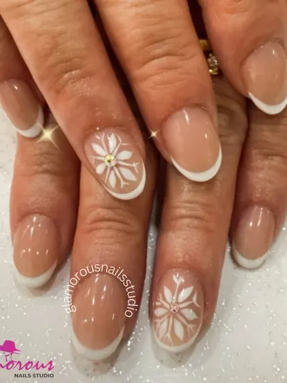 A beautiful winter-themed French manicure. This elegant design features classic white tips with accent nails adorned with a delicate white snowflake and a central rhinestone.