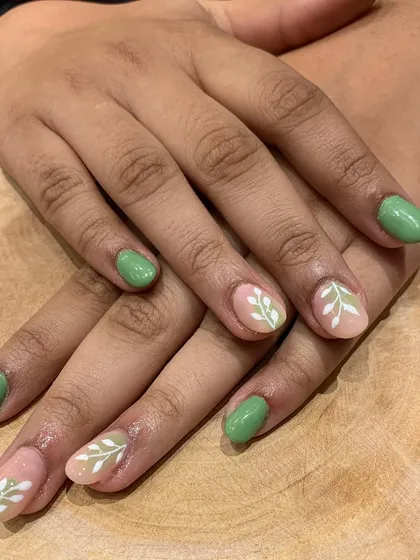 We love playing with negative space. This nail art combines solid pastel green nails with accent nails that use a clear base to showcase hand-painted white leaf patterns.
