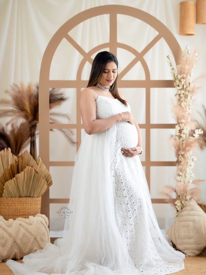 A serene solo portrait of a mom-to-be in a delicate white lace and tulle gown, set against our popular boho window arch.