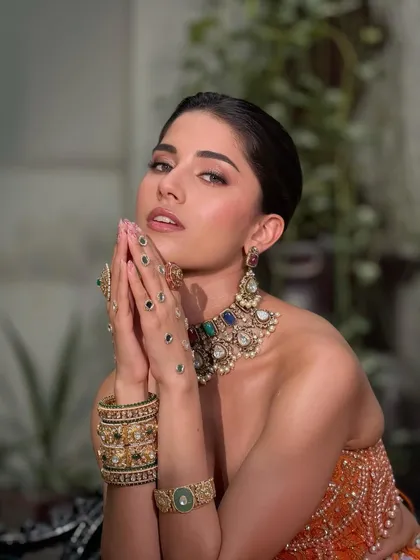 A striking pose showing the dewy, flawless base that catches the light just right. The eyes are minimal but striking with earthy tones and a touch of highlight.
