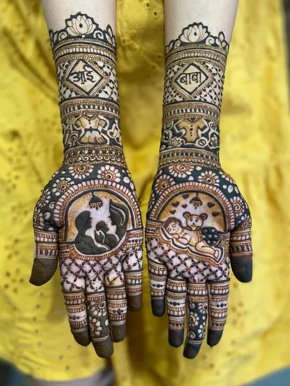 A beautiful maternity mehandi featuring a silhouette of a mother cradling her bump and a sleeping baby, with 'आई' and 'बाबा' written on the arms.