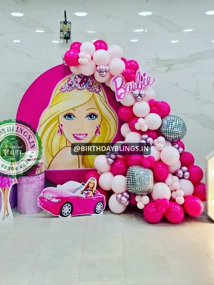 This Barbie party features a large character graphic on a round backdrop, a pink convertible car cutout, and a light-up number '6'. The disco ball balloons add a touch of sparkle and fun.