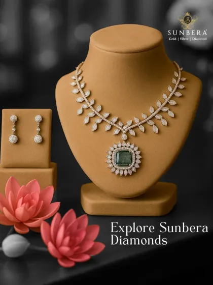 An opulent diamond necklace set featuring a large emerald centerpiece surrounded by a sunburst of diamonds and leaf-like motifs along the chain. This is a true showstopper for bridal and high-end collections.