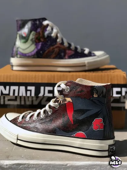 A dark and detailed Naruto theme on a pair of classic Converse high-tops. One shoe features the villain Orochimaru in a cosmic setting, while the other shows a menacing Itachi Uchiha from the Akatsuki clan.