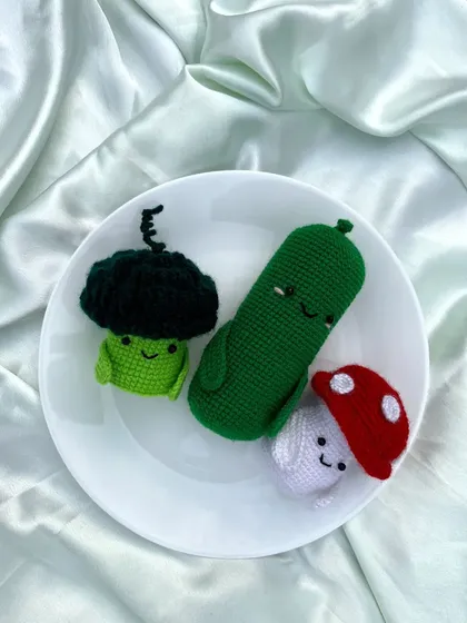 I also enjoy making quirky and fun crochet creations, like this set of smiling vegetables: a broccoli, a pickle, and a mushroom.