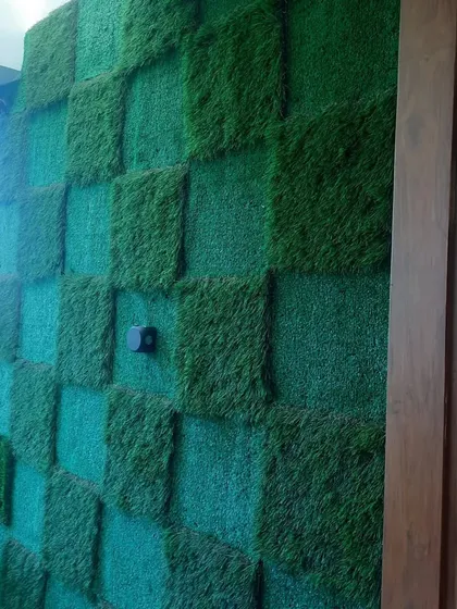 A unique checkerboard pattern created using two different piles of artificial grass. This design adds a playful and modern touch to an otherwise simple balcony wall.