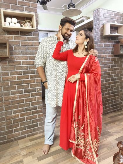 A happy Karwachauth moment with my husband, wearing my festive red outfit and elegant earrings.