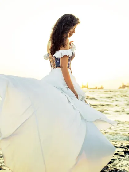 The back of a dress can be just as important as the front. This backlit shot from the beach photoshoot highlights the design details and the flowing white skirt against the golden hour sun.