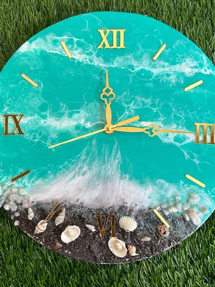 A vibrant turquoise ocean clock with a dark sand beach and delicate shells.