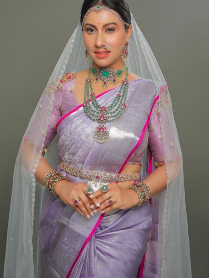 The exquisite diamond and emerald jewelry adds a layer of opulence to the soft lavender silk.