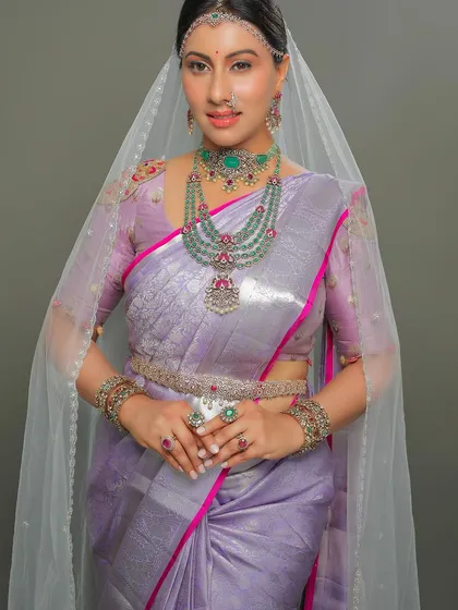 The exquisite diamond and emerald jewelry adds a layer of opulence to the soft lavender silk.