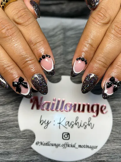 A bold black glitter set with negative space French tips and 3D black bows for a chic, modern look.