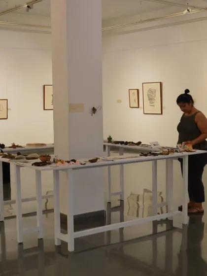 A visitor browses the long tables of found objects and small artworks at the 'Bring me Flowers' exhibition.