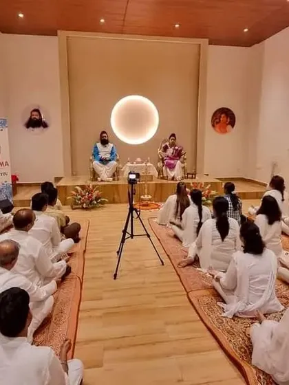 A wide view of a satsang at our Bangalore spiritual centre, with participants seated on the floor, fully absorbed in the session. The setup is simple and traditional, focusing on the spiritual experience.