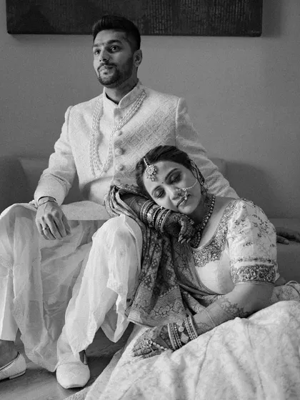 A bride rests her head on her groom's lap, a moment of quiet comfort and trust. This black and white image speaks volumes about their deep connection and the peace they find in each other.