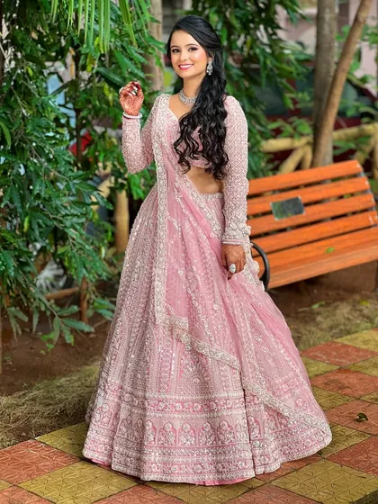 A full-length shot showing the bride's stunning pink lehenga. The simple diamond set is the perfect choice, adding elegance without distracting from the outfit's heavy embroidery.