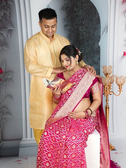 A beautiful blend of tradition and intimacy. The couple shares a quiet moment while reading, with the mom-to-be elegantly dressed in a pink saree.