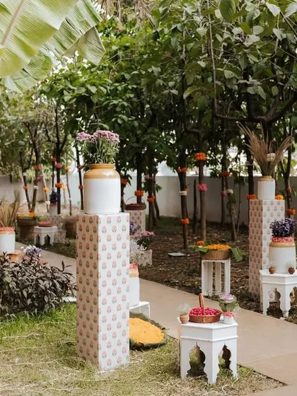 The walkway was lined with banana trees and other local plants, with their trunks wrapped in colorful floral garlands. This created a natural and festive pathway for guests.