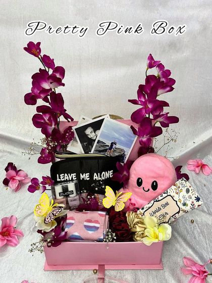 My "Pretty Pink Box" is a vibrant hamper for a sister, filled with fun items like a reversible octopus plushie, photos, and pampering essentials, all decorated with orchids.